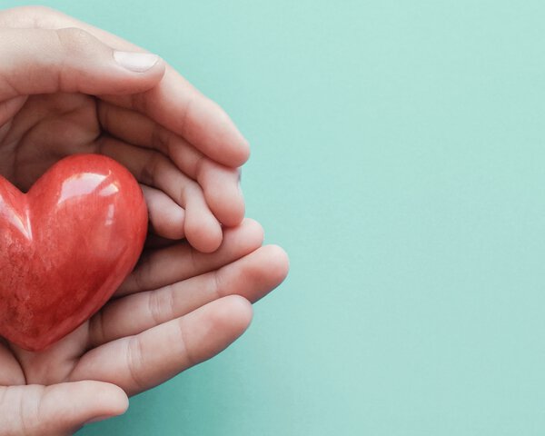 Zwei Hände halten rotes Herz aus Stein | © Sewscream - Stock.adobe